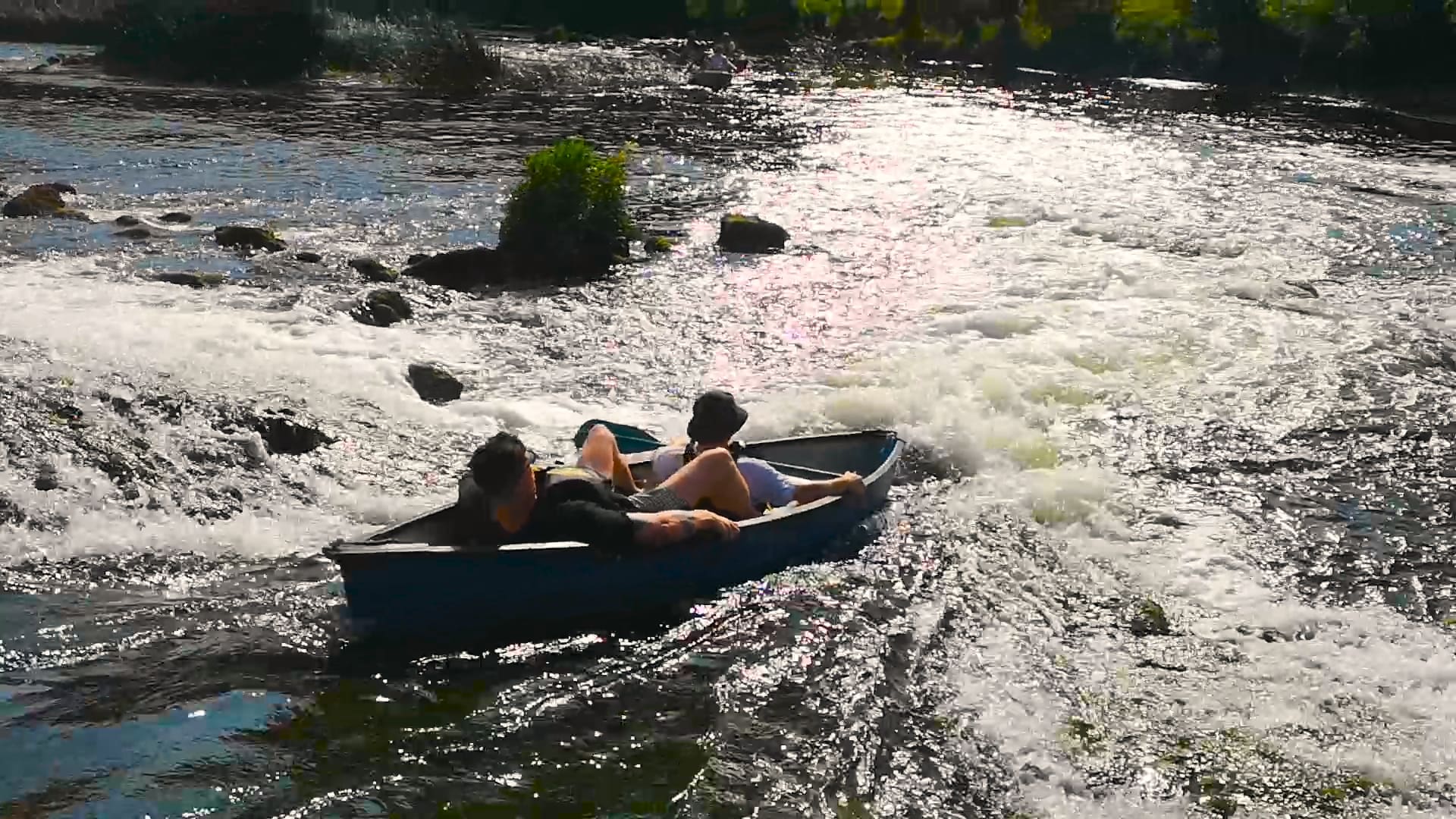 Two people paddling in a blue canoe on a calm Irish river surrounded by lush greenery.